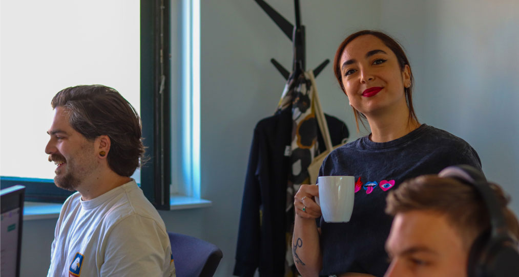 Collega Sibel glimlacht en drinkt koffie